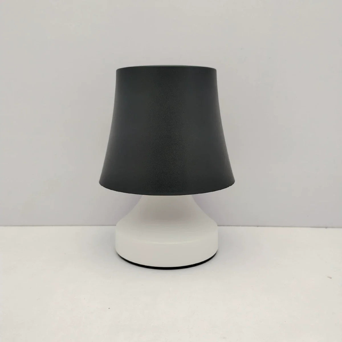 Table lamp with black shade and white base on a white background