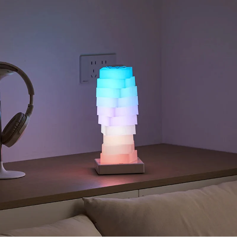 Colorful lamp on a wooden surface with headphones and books in the background