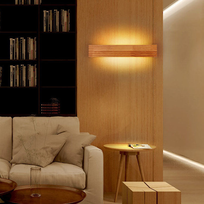 Modern living room with beige sofa, wooden side table, and wall-mounted light fixture.