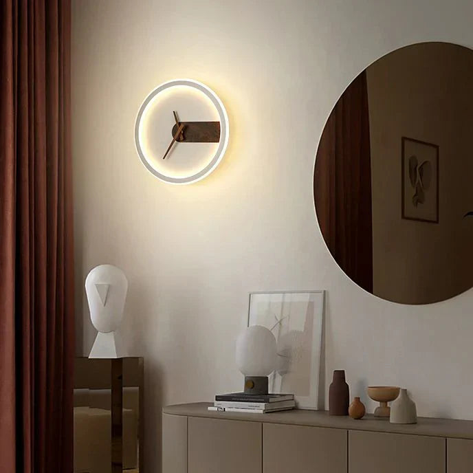 Modern wall clock on a neutral wall with decorative items below.