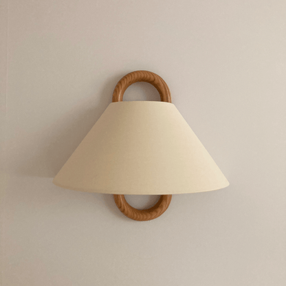 Wall-mounted lamp with beige shade and wooden handle on a plain wall.