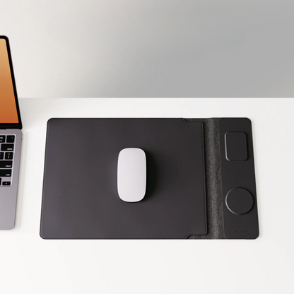 Black graphic tablet with a white mouse on a white surface next to a laptop.