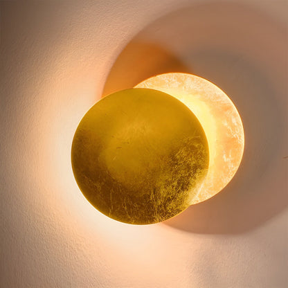 Round wall light fixture casting a warm glow on a textured wall.