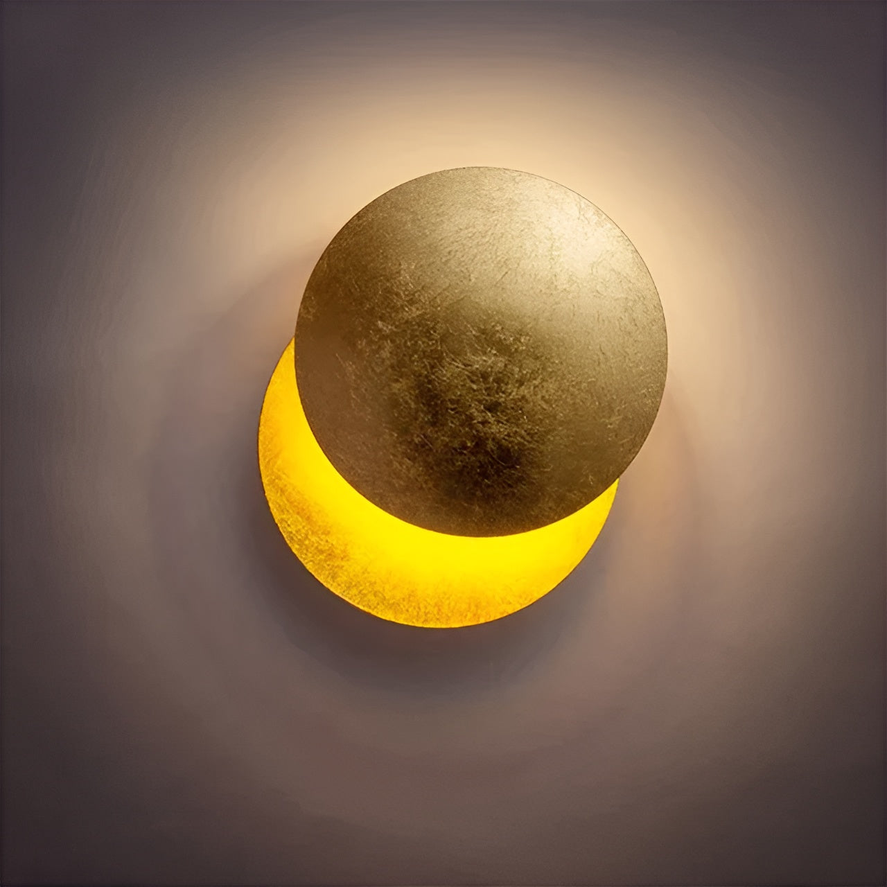 Round wall light fixture with gold and yellow gradient on a dark background