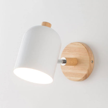 Wall-mounted light fixture with white shade and wooden base on a plain background