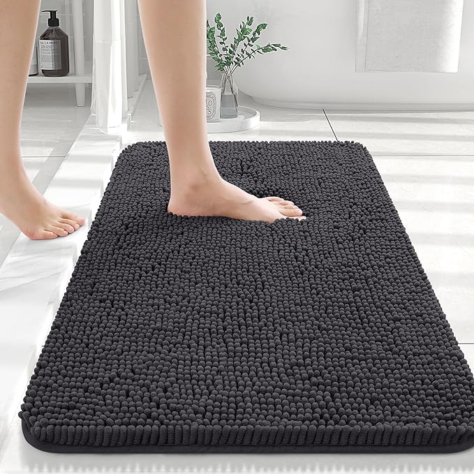 Person stepping onto a black bath mat in a bathroom setting.