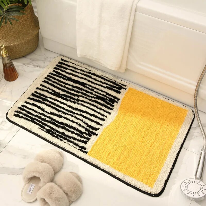 Multicolored bath mat with black, white, and yellow pattern on a bathroom floor.