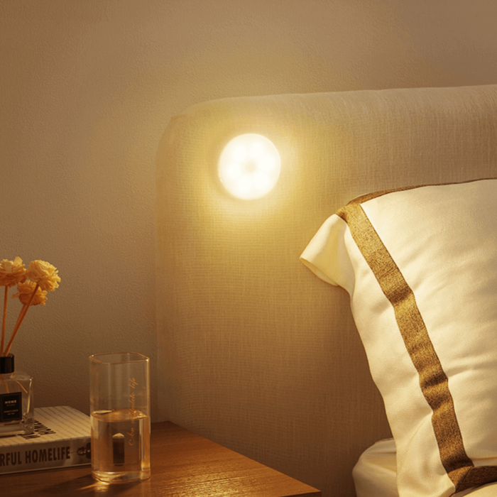 Bedroom nightstand with a lit night light, glass of water, and book.