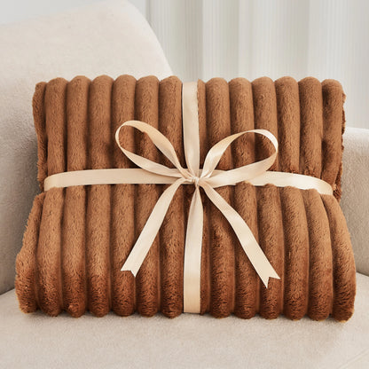 Brown textured blanket with a beige ribbon on a light-colored surface