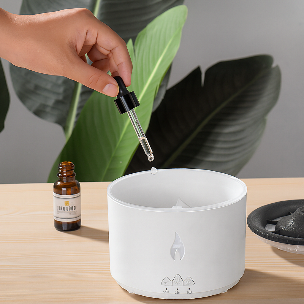 Hand using a dropper to add liquid to a white diffuser with a plant in the background