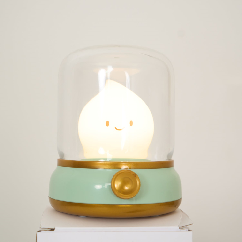 Cute lamp with a smiley face inside a glass dome on a white surface.