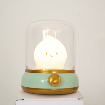 Cute lamp with a smiley face inside a glass dome on a white surface.