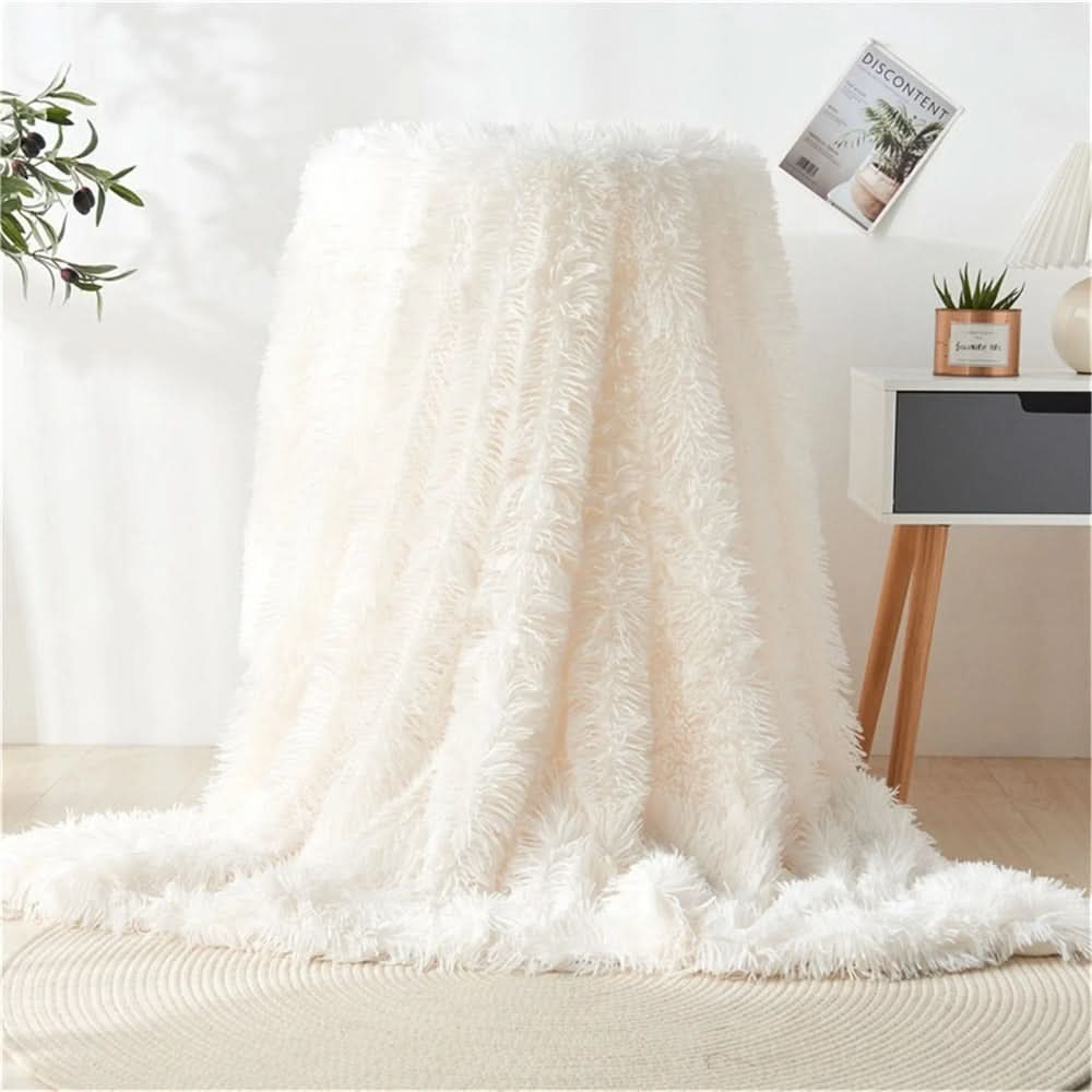 White fluffy blanket draped over a couch in a cozy living room setting.