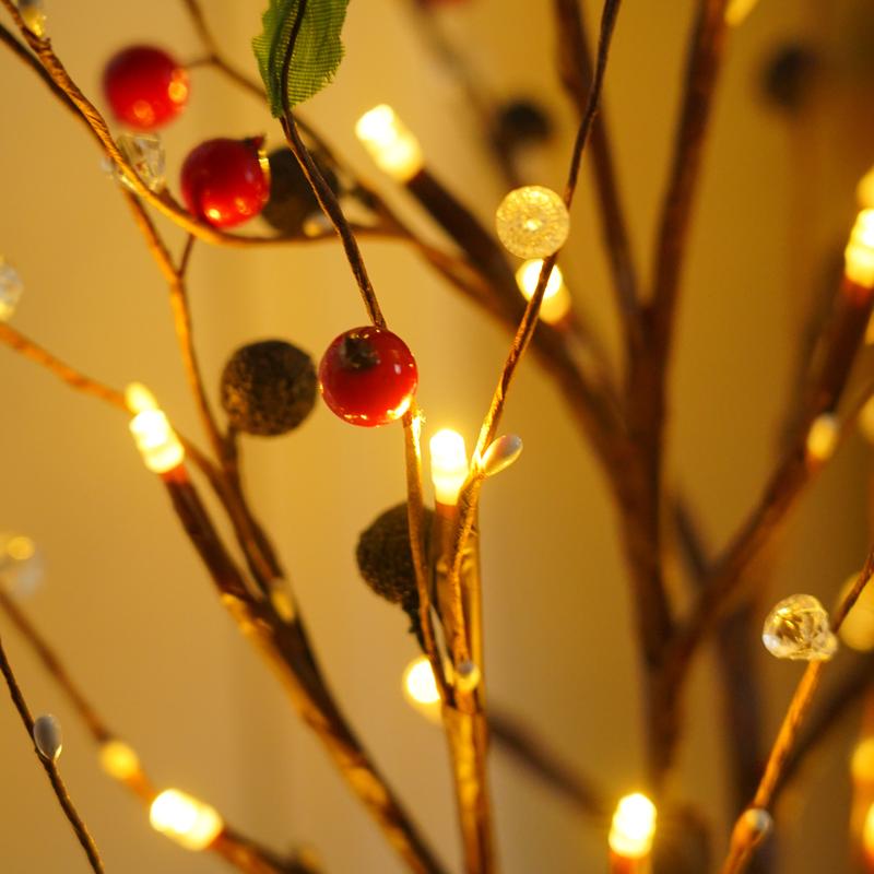 Decorative branch with red berries and string lights against a warm background