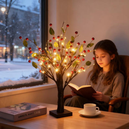 Child reading a book next to a decorative tree with lights on a table by a window with snow outside.