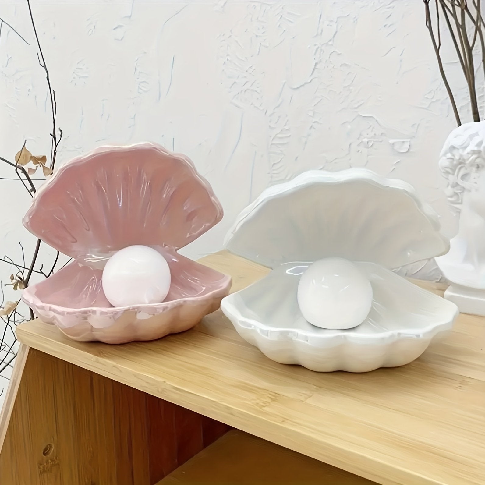 Pink and white ceramic shell-shaped containers with eggs on a wooden surface.
