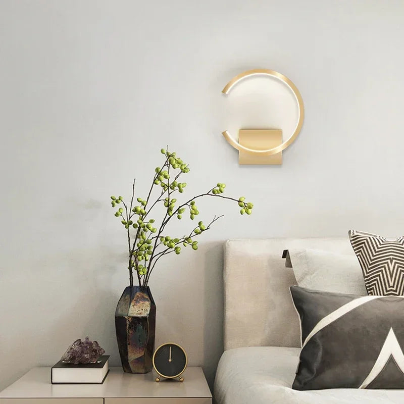 Modern interior design with a wall lamp, vase with green branches, and decorative items on a table.