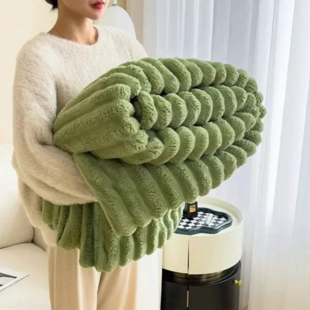 Person holding a large green knitted blanket in a living room setting.