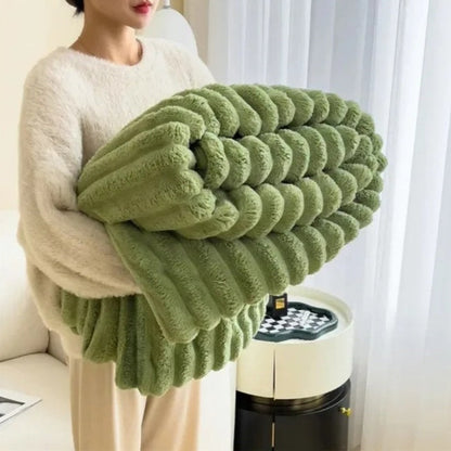 Person holding a large green knitted blanket in a living room setting.