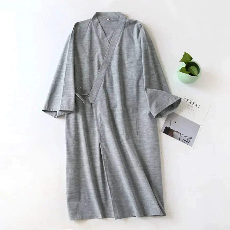 Gray robe on a white surface with a small plant and card in the background