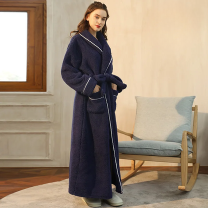Woman wearing a long navy robe in a cozy room with a rocking chair and window.