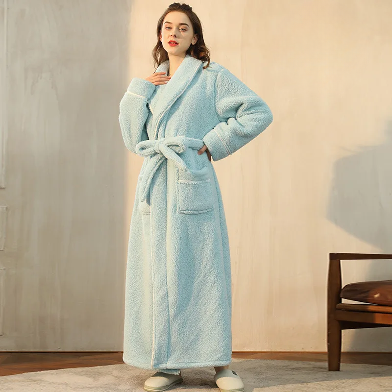 Woman wearing a light blue robe in a room with wooden flooring and a chair.