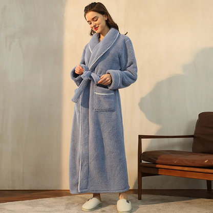 Woman wearing a blue robe standing in a room with a wooden chair and cushion.