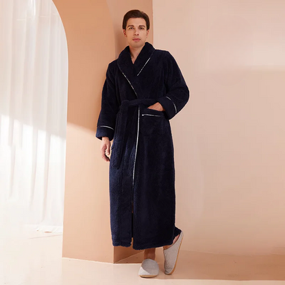 Man wearing a navy blue robe standing in a room with beige walls and white curtains.