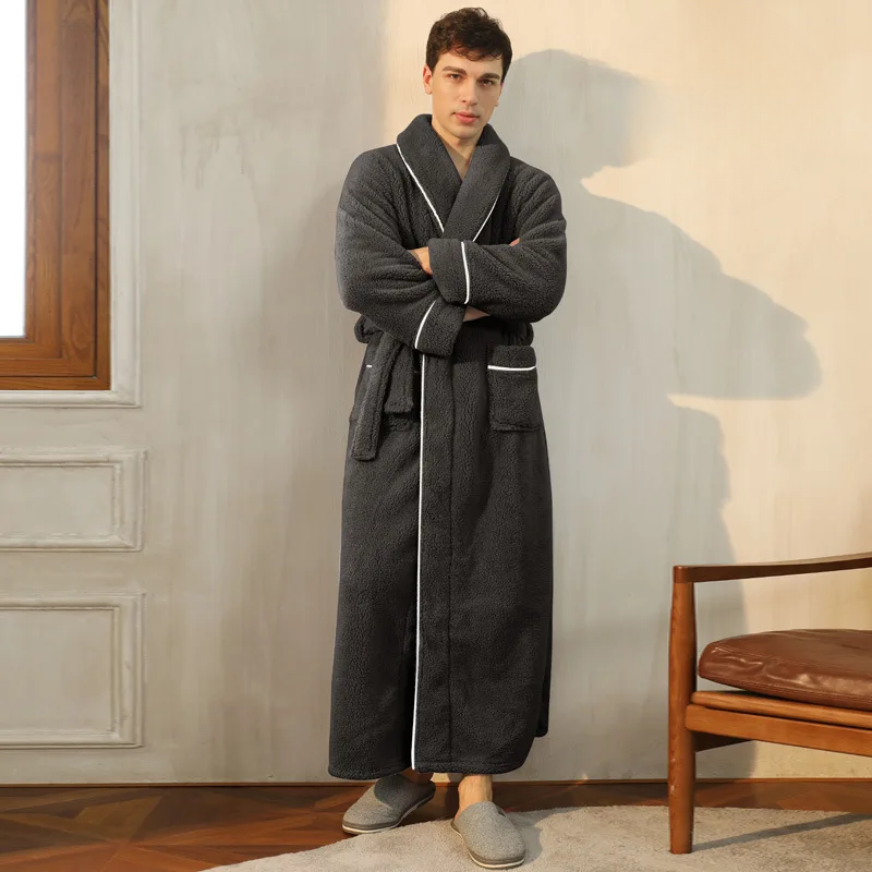 Man wearing a long dark gray bathrobe with white trim in a room with a wooden chair and window.