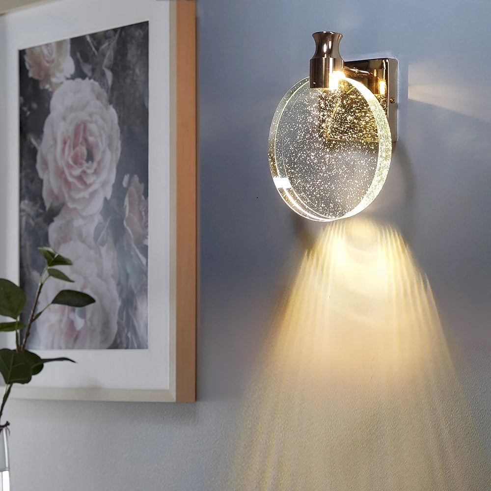 Wall-mounted light fixture with a decorative glass shade on a wall next to a floral painting.