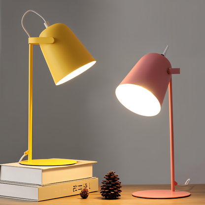 Two table lamps, one yellow and one pink, on a wooden surface with a gray background.