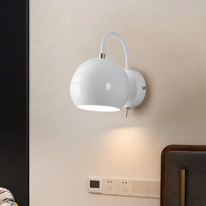 White wall-mounted lamp on a beige wall with a dark curtain and wooden furniture.
