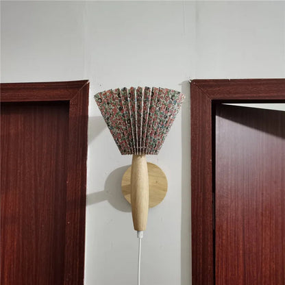 Decorative wall sconce with floral patterned shade between two wooden door