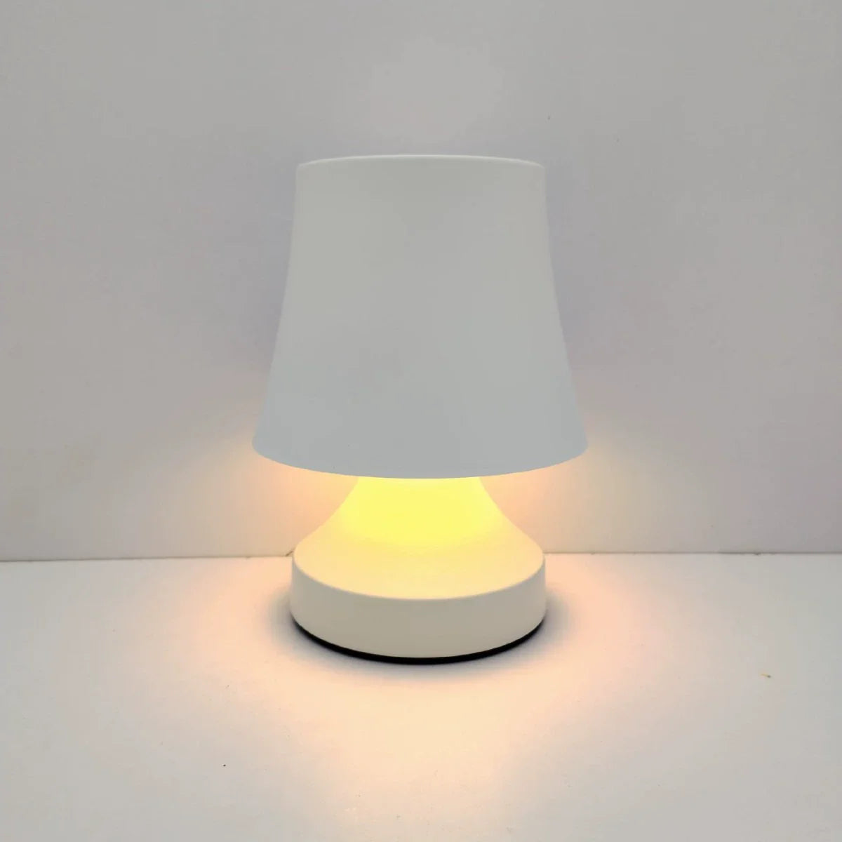 Small table lamp with a white shade and base on a light gray background