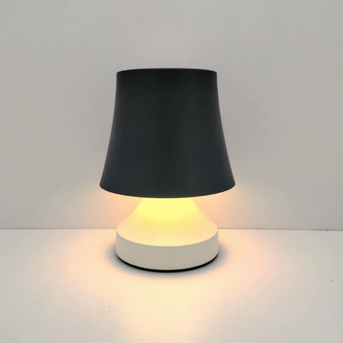 Small table lamp with black shade and white base on a light gray background