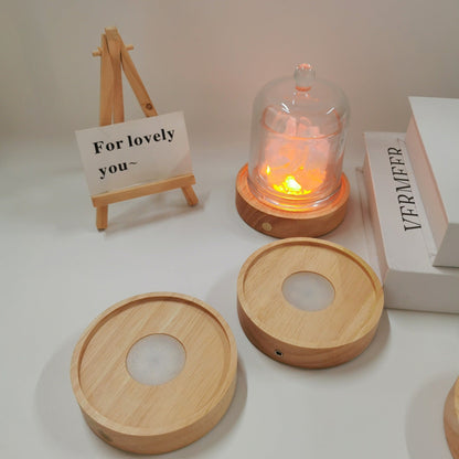 Wooden diffuser with glowing light inside, surrounded by wooden lids on a white surface.