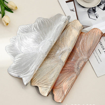 Three decorative platters with leaf-like designs in silver, gold, and rose gold on a light surface.