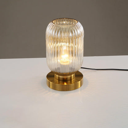 Table lamp with ribbed glass shade and gold base on a white surface.