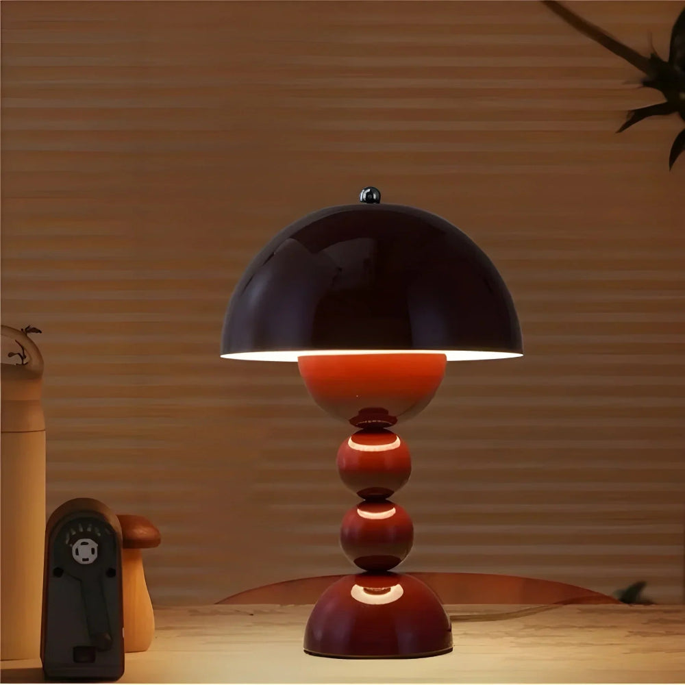 Table lamp with a black shade and red base on a wooden surface.