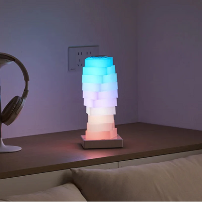 Colorful lamp on a wooden surface with headphones and books in the background