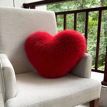Red heart-shaped pillow on a gray chair with a blurred green outdoor background