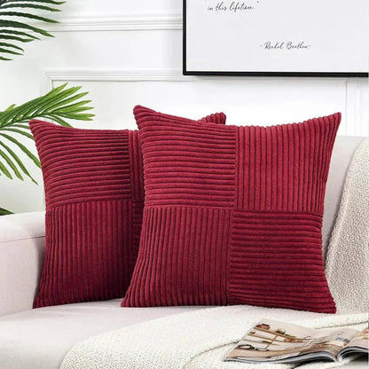 Two red textured pillows on a white couch with a framed quote in the background.