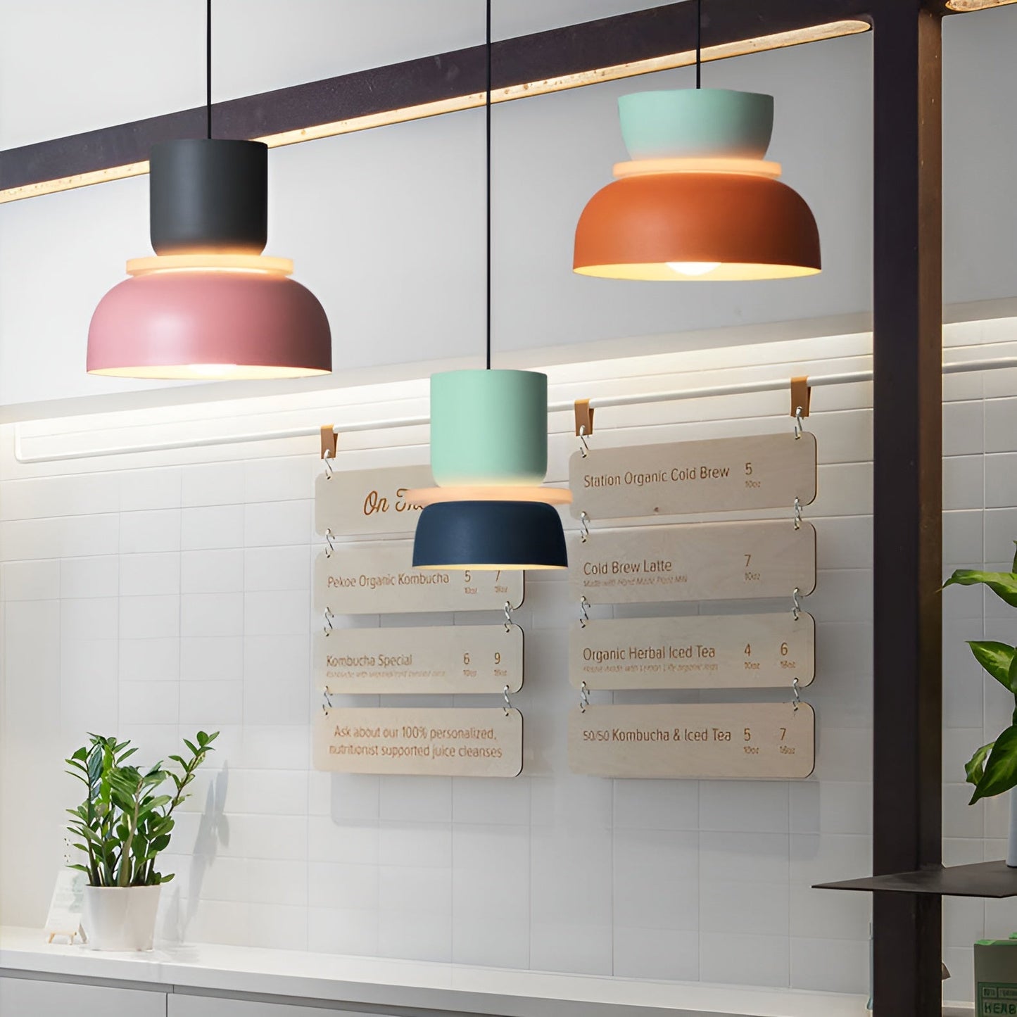 Colorful pendant lights hanging above a counter with menu boards in the background.