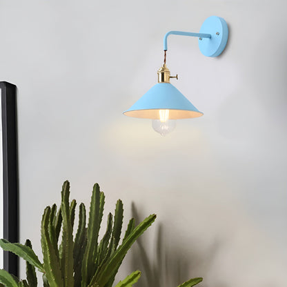 Wall-mounted light fixture with a blue shade and gold base on a white wall, next to a cactus plant.
