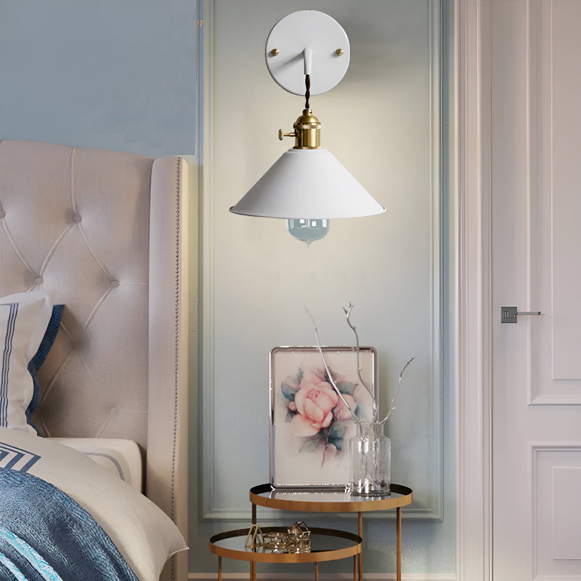 Decorative wall lamp above a small round table with a floral painting in a bedroom setting.