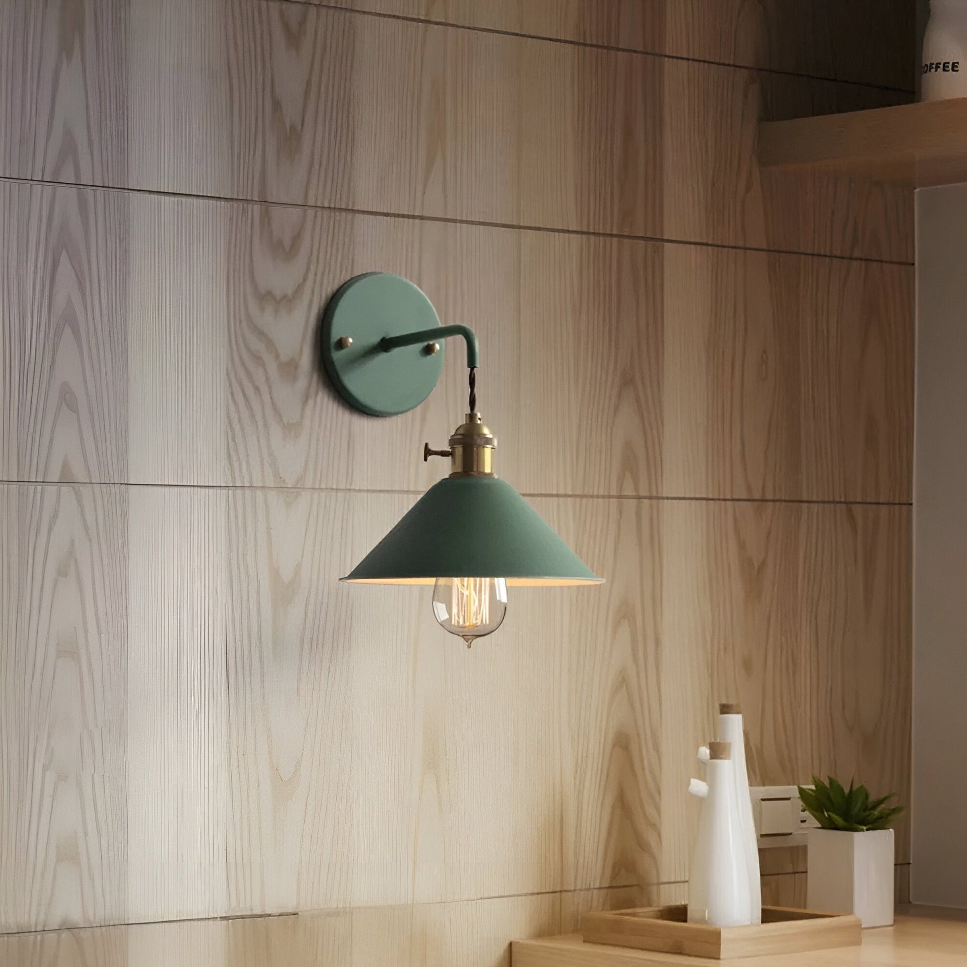 Green wall-mounted lamp in a room with wooden walls and a desk.