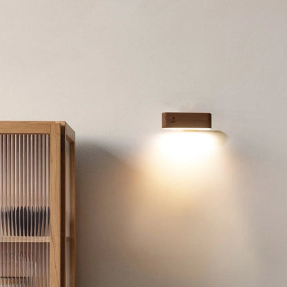 Wooden wall lamp casting light on a neutral wall next to a wooden bookshelf.