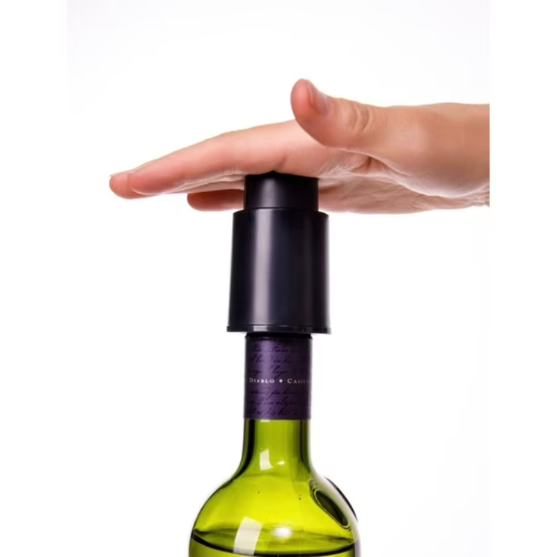 Hand holding a black wine bottle stopper on a green wine bottle against a white background