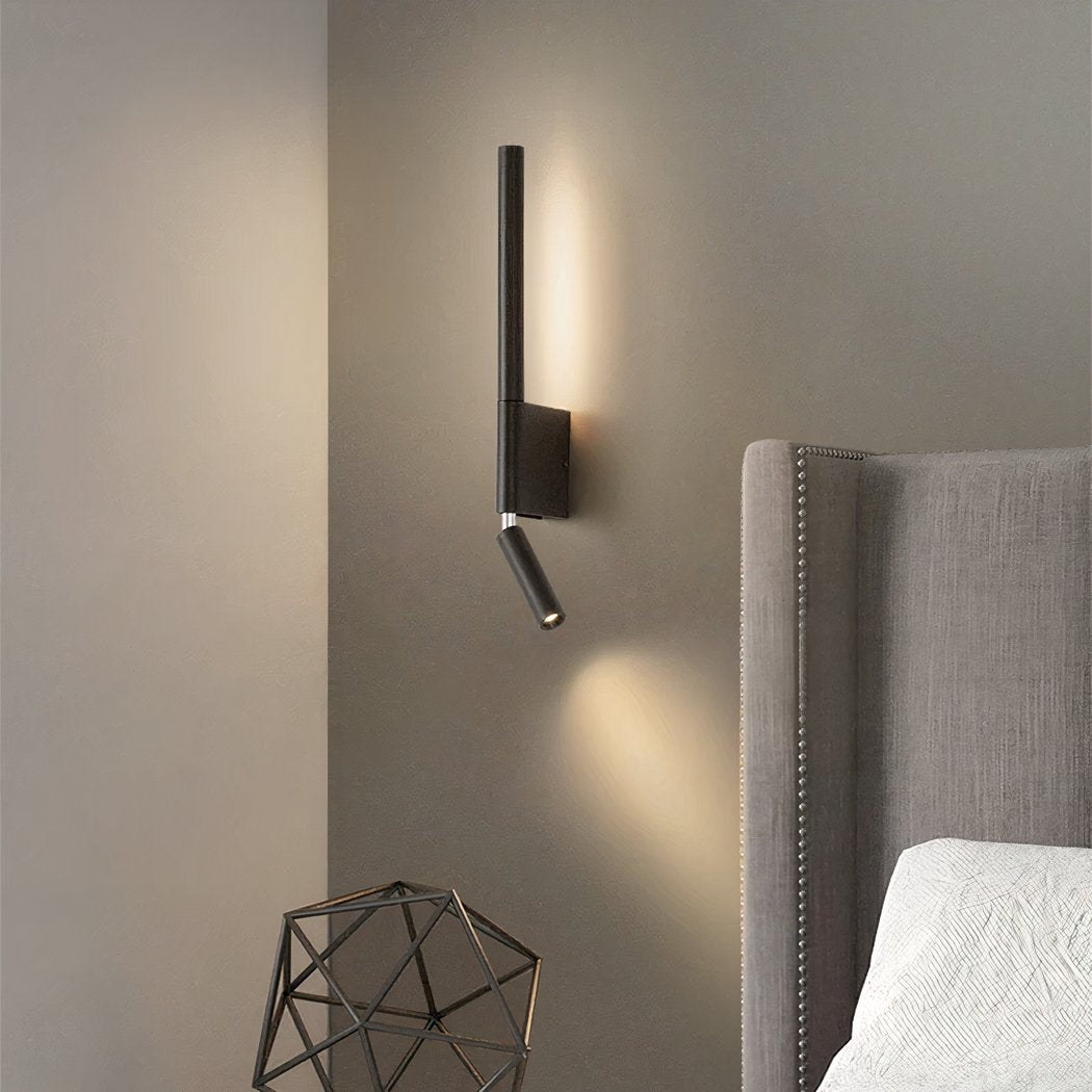 Modern wall-mounted light fixture on a neutral wall next to a upholstered headboard.