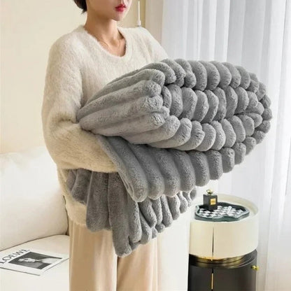 Person holding a large gray textured blanket in a living room setting.